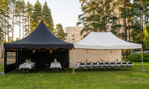 4x10m kokoinen yhdistelmäteltta kerrostalon pihamaalla. Sisällä tyylikkäästi katetut juhlapöydät ja tuolit.
