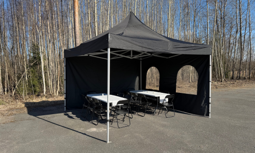 4x4m musta juhlateltta asfaltoidulla pihamaalla.