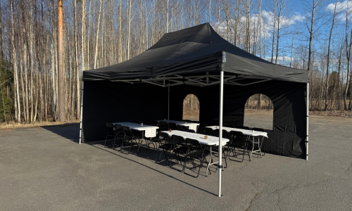 4x6m musta juhlateltta asfaltoidulla pihamaalla.